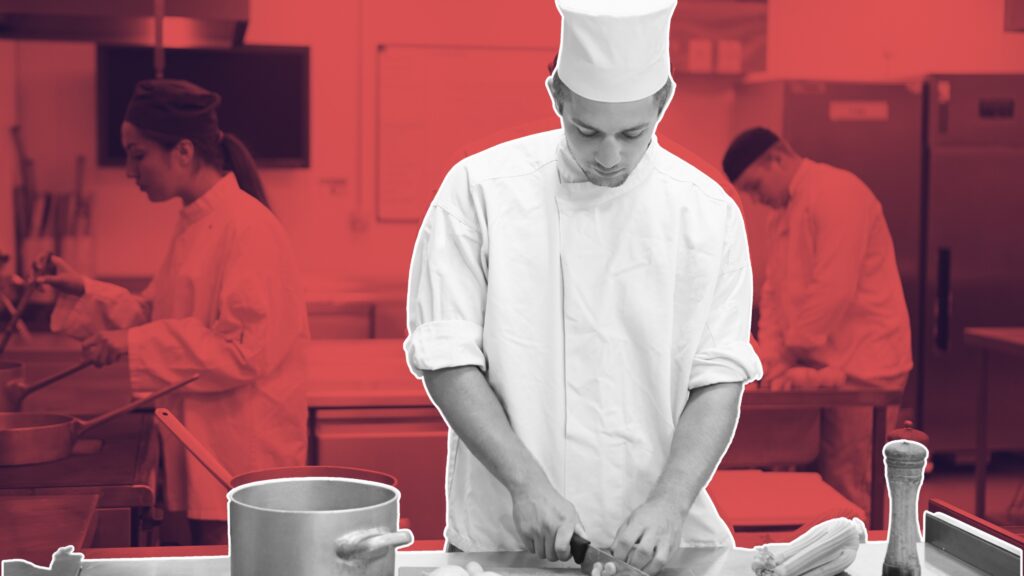 Chef reviewing prep list on kitchen wall clock in background, free time management courses for hospitality